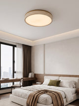 Round travertine ceiling light lit above a bed facing a city window