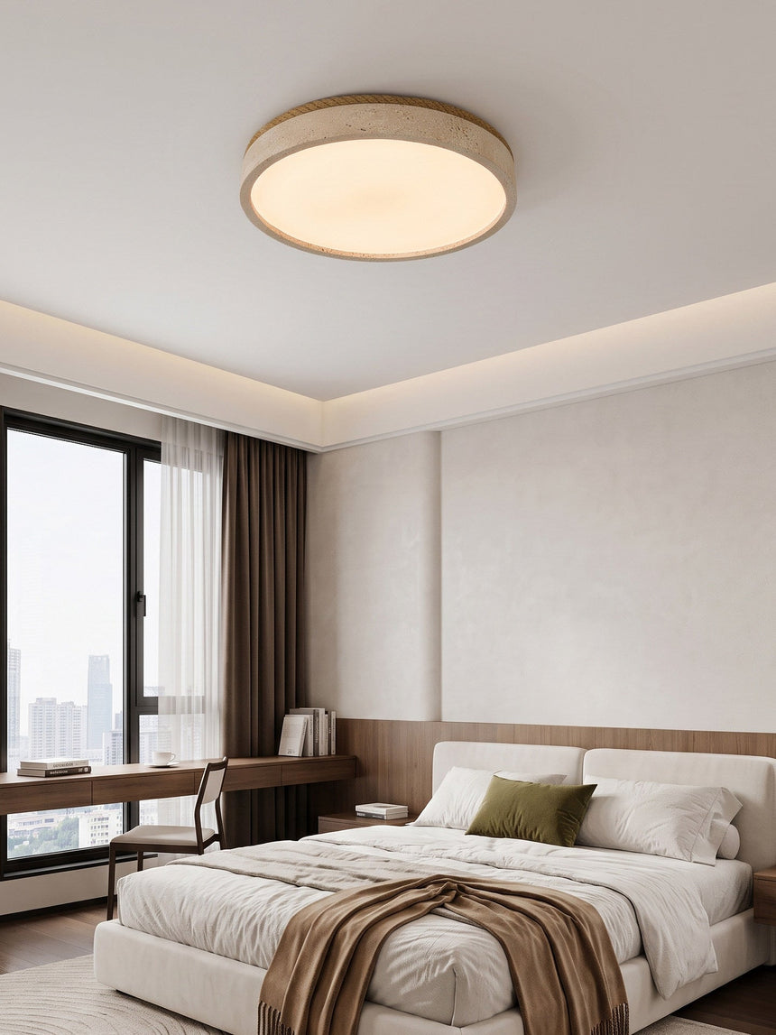 Round travertine ceiling light lit above a bed facing a city window