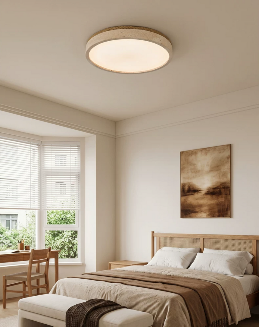 Round travertine ceiling light above a wood bed frame beside a bright window