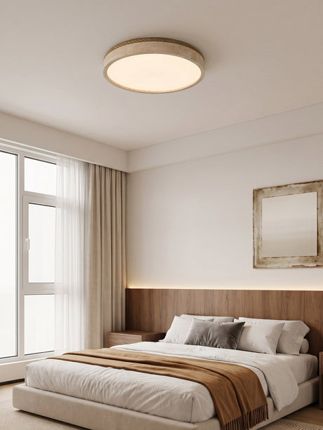 Round travertine ceiling light in a bedroom with a tall window and a framed print