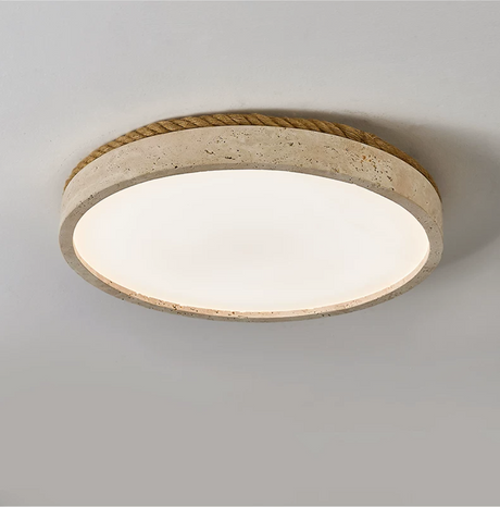 Round travertine ceiling light seen from below at an angle on a plain backdrop