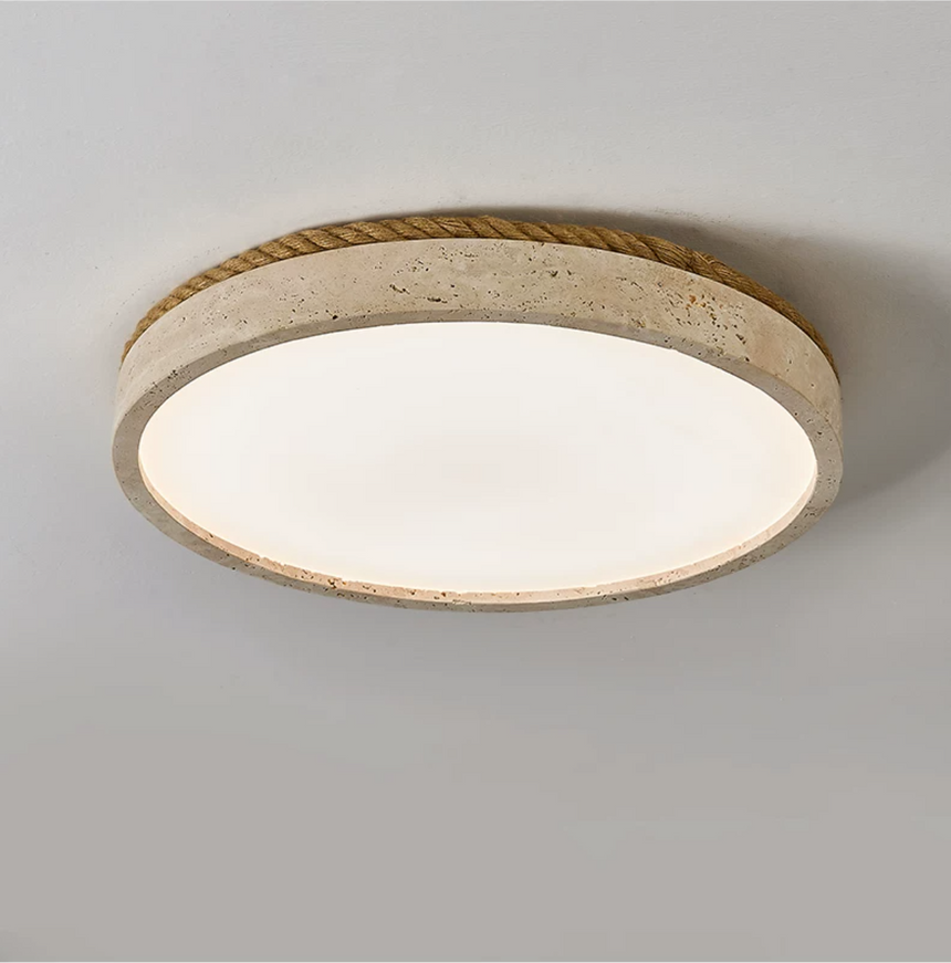 Round travertine ceiling light seen from below at an angle on a plain backdrop
