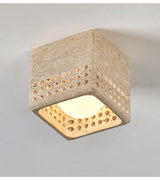 Square travertine block ceiling light lit, showing light through the drilled holes