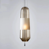 An amber glass tube pendant lit with a white inner cylinder showing