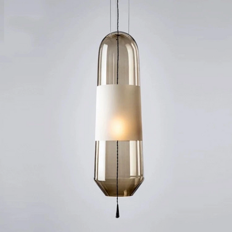 An amber glass tube pendant lit with a white inner cylinder showing