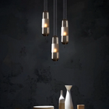 A group of tube pendants lit at different heights on a dark wall