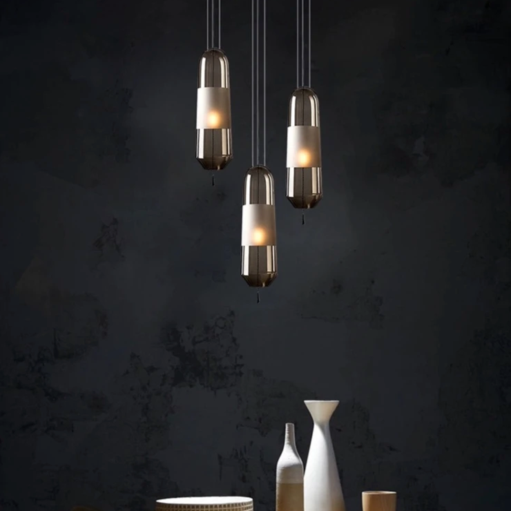 A group of tube pendants lit at different heights on a dark wall