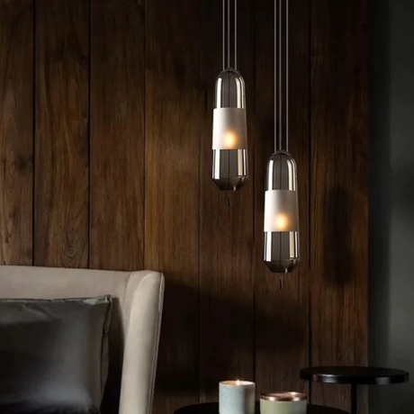 Three tube pendants at staggered heights beside a wooden wall and a chair