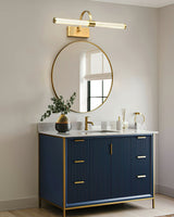 Brass arch and tube lit above a round mirror over a deep blue fluted vanity unit