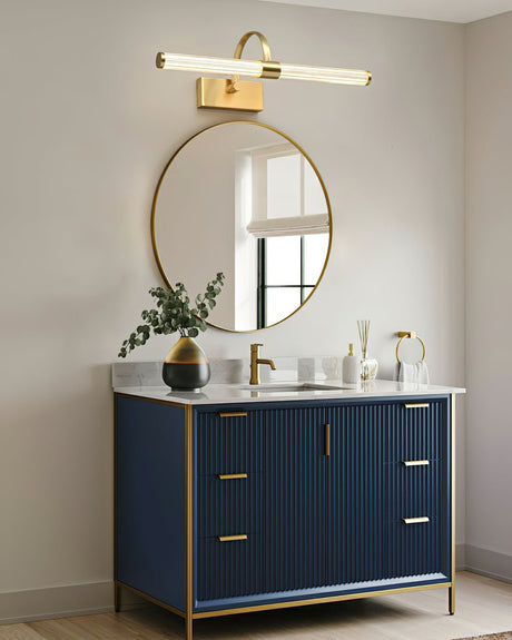 Brass arch and tube lit above a round mirror over a deep blue fluted vanity unit