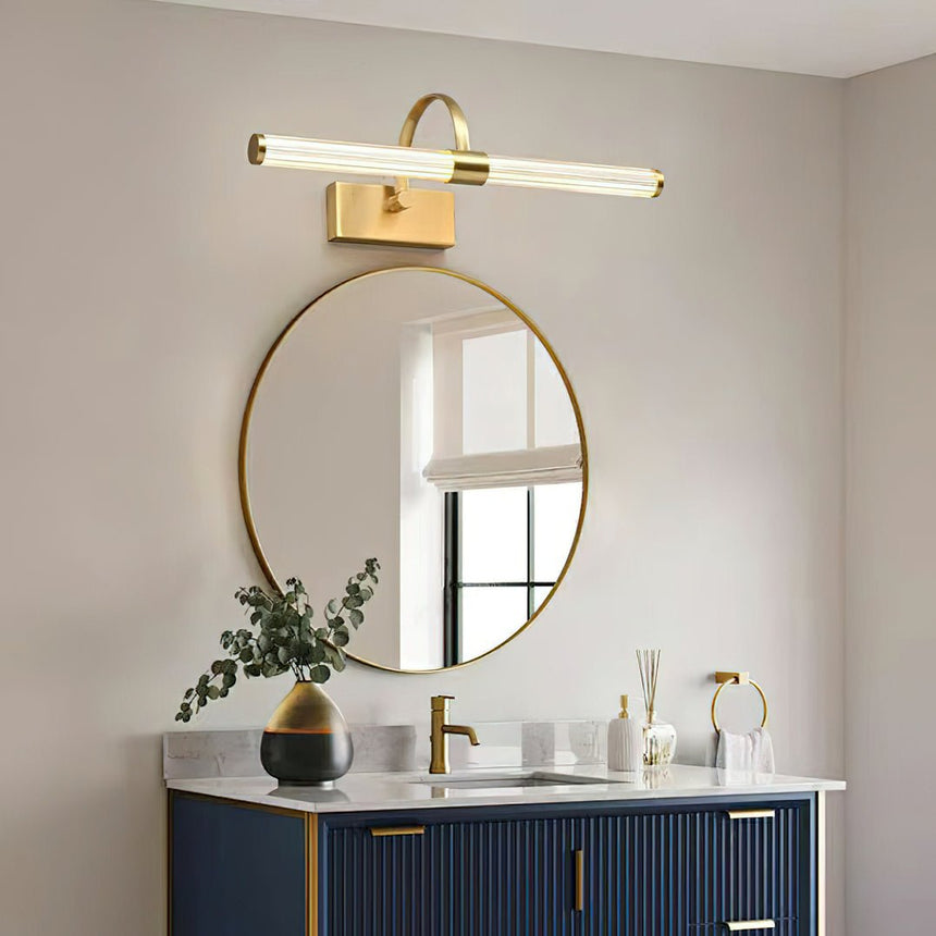 Brass arch and ribbed tube lit above a round mirror on a blue fluted vanity
