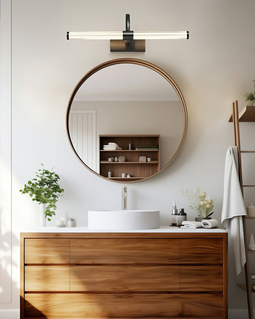 Arch and tube lit above a round mirror on a walnut vanity with a stone basin