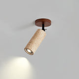 Travertine tube angled on its base, the beam falling across a pale wall