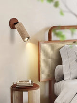 Travertine tube lit on a bedside wall next to a rattan headboard