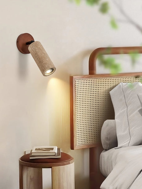 Travertine tube lit on a bedside wall next to a rattan headboard