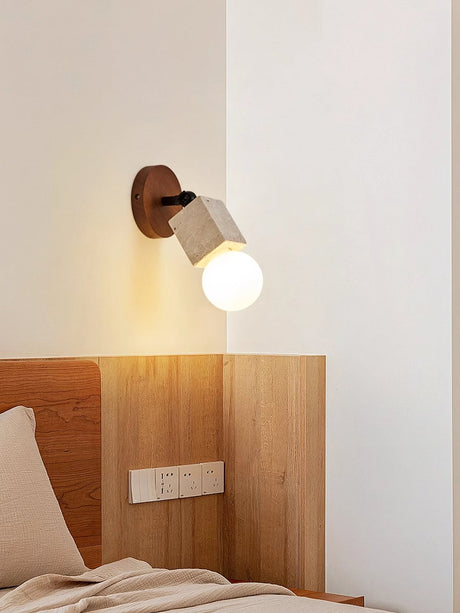 Travertine tube lit above a bed with an open bulb over the headboard