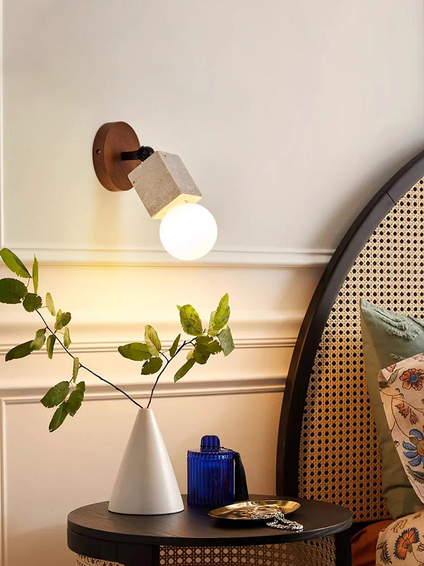 Travertine tube lit above a console table holding a vase and a plant