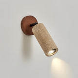 Travertine tube tilted down on its walnut base, throwing a spot on the wall