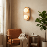 Sconce lit on a plaster wall beside a tan armchair, a plant and a window