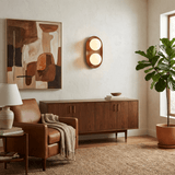 Sconce lit beside a framed artwork above a sideboard with a plant nearby