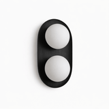 Black capsule with two opal globes set into its face, seen unlit