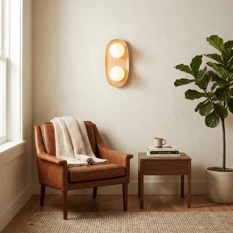 Sconce lit above a leather armchair with a throw, a side table and a plant
