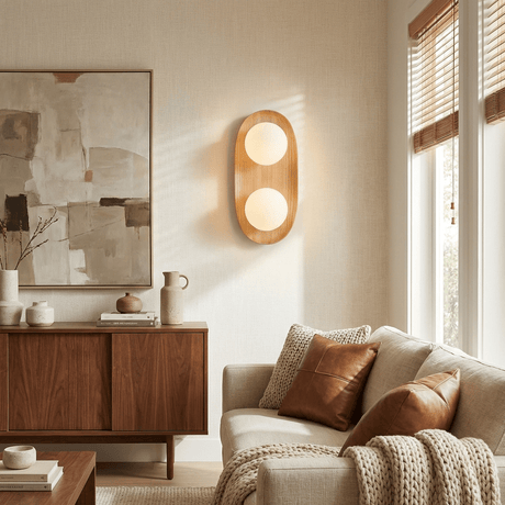 Sconce lit above a walnut sideboard beside a sofa and a framed artwork