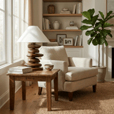 Unique table lamp lit on a wood side table beside an armchair