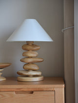 Unique table lamp in light wood on a dresser beside a wall