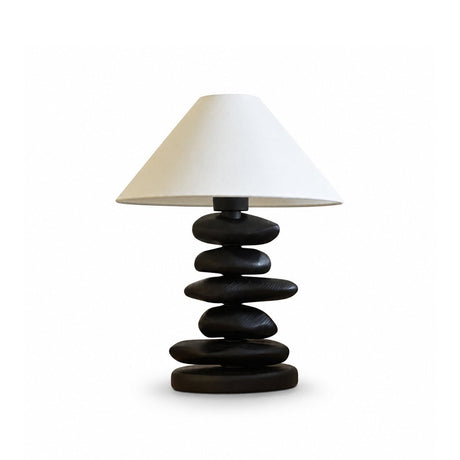 Unique table lamp with a matte black pebble stack on a plain ground