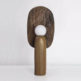 Bronze toned backplate table lamp lit, the carved grain catching the light