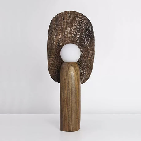 Bronze toned backplate table lamp lit, the carved grain catching the light
