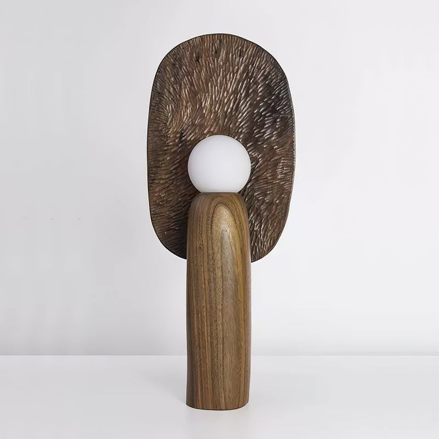 Bronze toned backplate table lamp lit, the carved grain catching the light