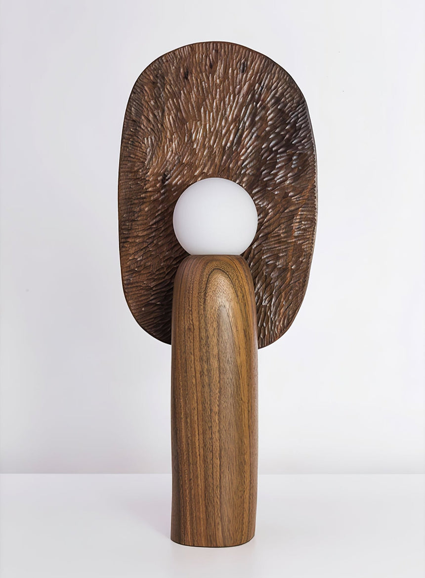 Table lamp with a bronze toned carved backplate and an opal glass globe