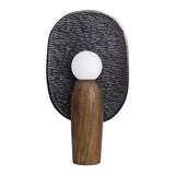 Charcoal backplate table lamp lit, the opal globe glowing against the texture