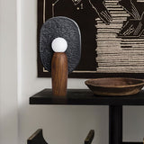 Totem table lamp on a dark console below a framed abstract artwork