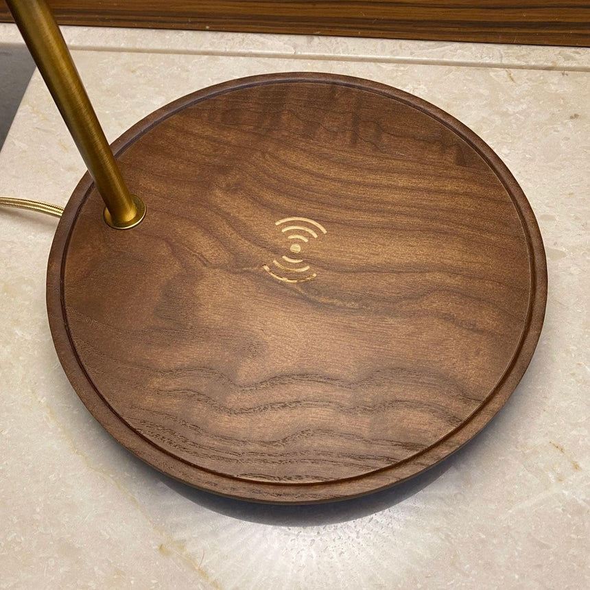 Close view of the charging symbol engraved in the center of the walnut base