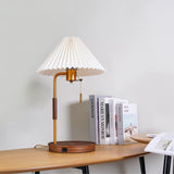 Table lamp lit on a wood desk beside books and an open magazine