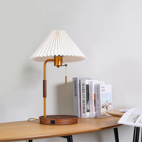 Table lamp lit on a wood desk beside books and an open magazine