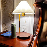 Table lamp lit on a round side table beside a dark armchair at night