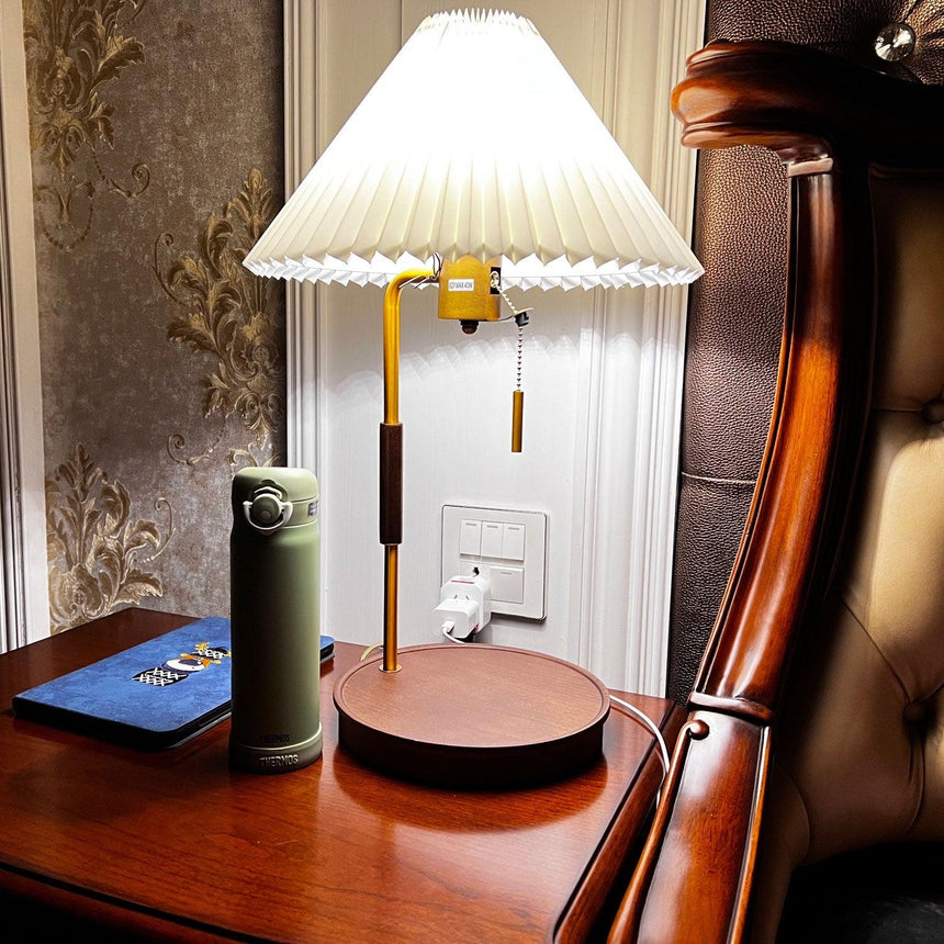 Table lamp lit on a round side table beside a dark armchair at night