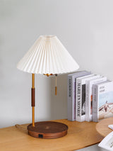 Table lamp unlit on a wood desk beside a row of standing books