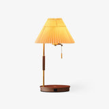 Table lamp with a pleated beige shade on a brass pole and a walnut disc base