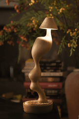 Cordless carved wood table lamp lit on a shelf among leaves and berries