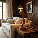 Cordless carved wood table lamp lit on a console behind a pale sofa