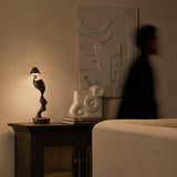 Cordless carved wood table lamp lit on a cabinet in a dim hallway