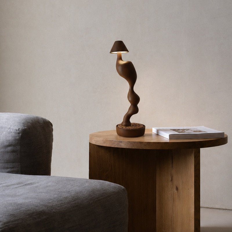 Cordless carved wood table lamp on a round side table beside a chair
