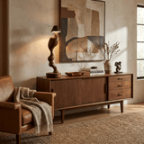 Cordless carved wood table lamp on a walnut sideboard beside a vase