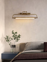 Bracket lit above a bed with a dark headboard beside a branch in a tall vase
