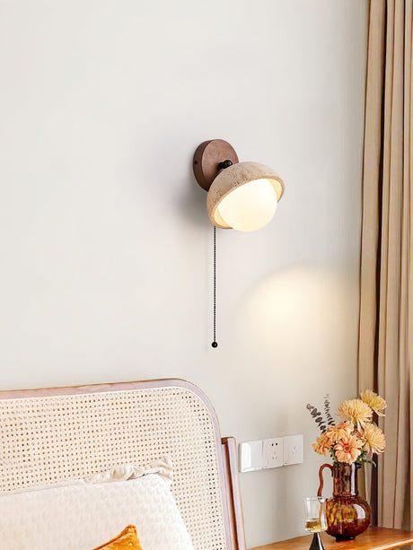 Single dome lit beside a cane headboard above a vase of dried flowers